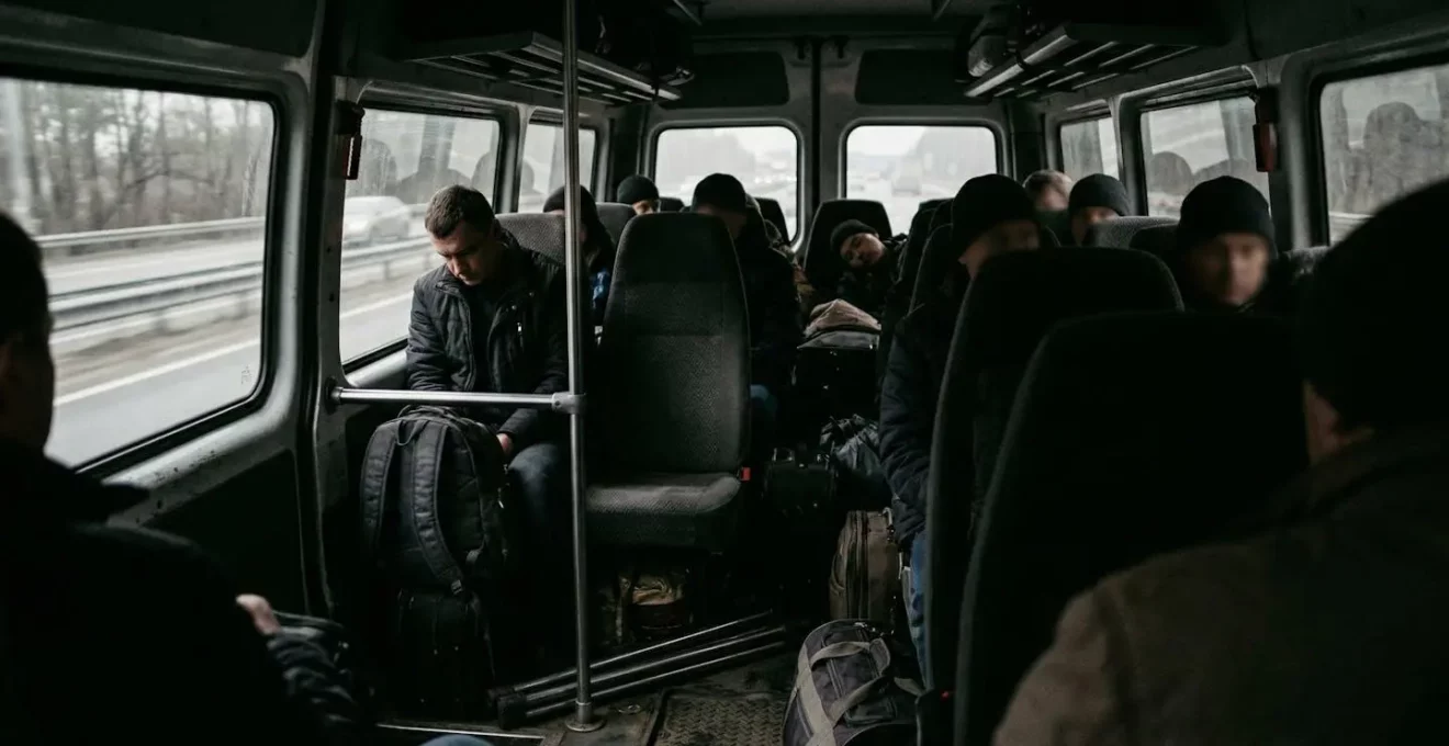 Intérieur d'une navette minibus avec quelques passagers assis et des bagages rangés, lumière naturelle entrant par les fenêtres